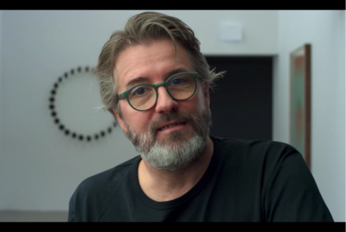 Olafur Eliasson, Danish-Icelandic artist, white bearded male with graying hair and green-rimmed glasses. He is wearing a black T-shirt.