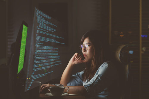 A female programmer staring at complex code in front of her computer